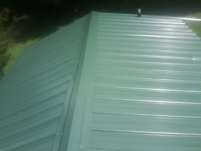 New green metal panels meeting at the ridge of a roof — Flat Roof Repair work by our crew in Ashland City
