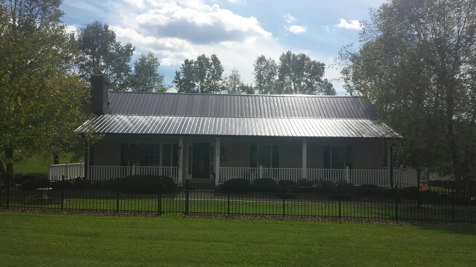 Gray metal roof on a brick ranch with a full width front porch — Gutter Guard Installation work by our crew in Ashland City