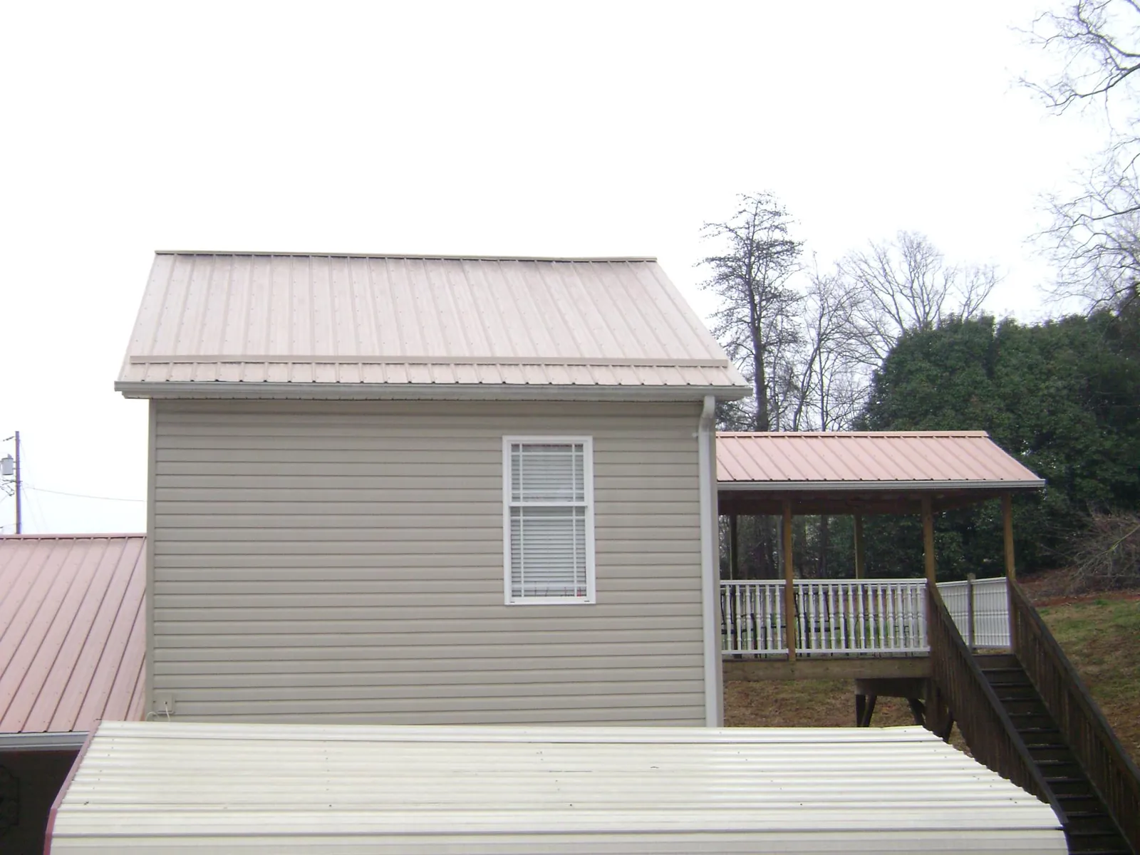 Tan metal roofs on a two story addition and attached porch, from a Roof Replacement job in Ashland City