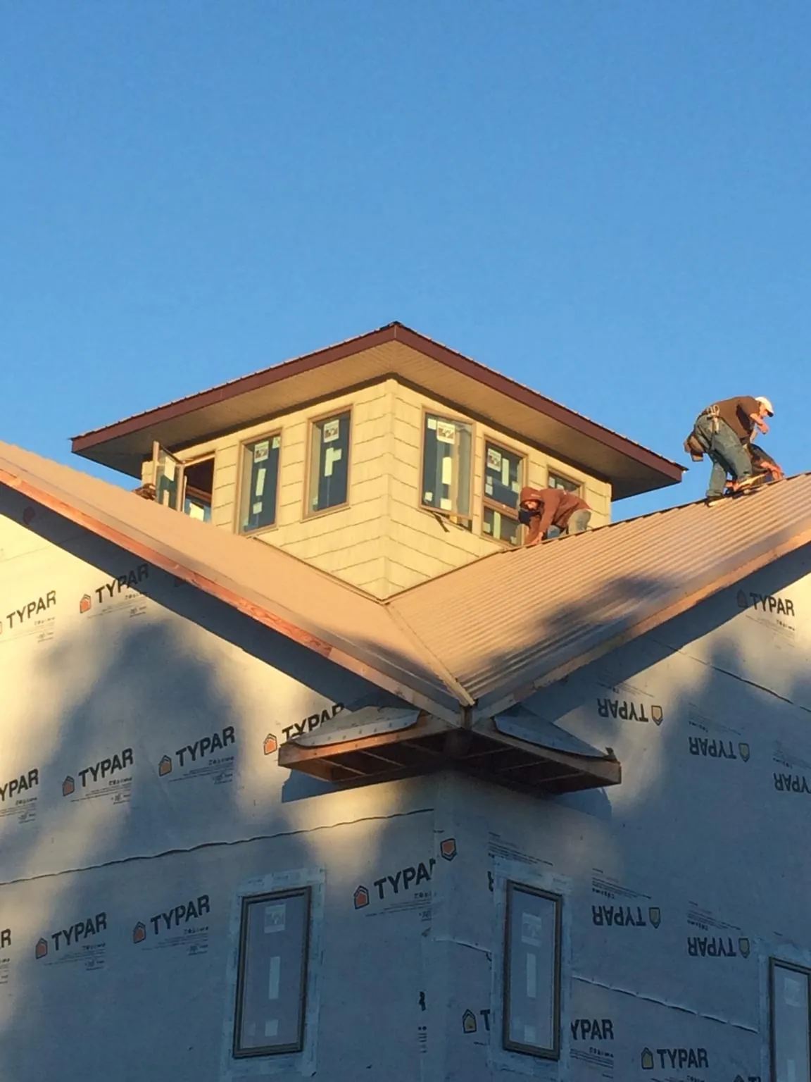 Roofers working around a rooftop cupola on a new metal roof at sunset — Roof Waterproofing in Ashland City by Roofing Brothers
